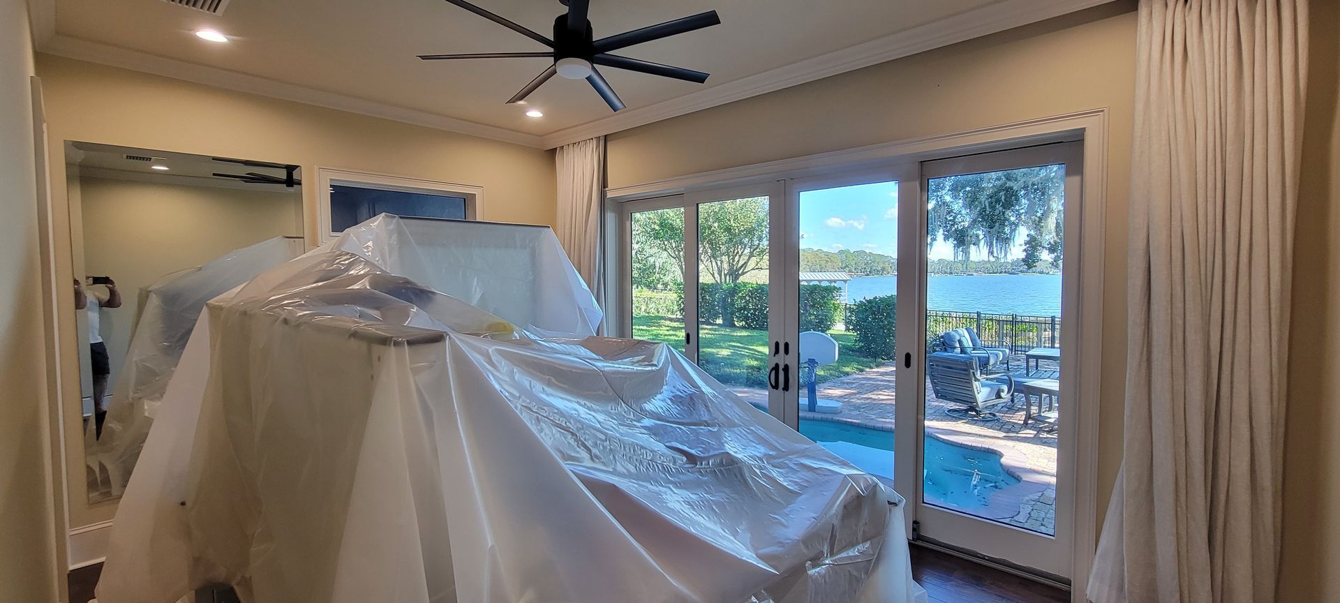 A room with a ceiling fan and a sliding glass door covered in plastic.
