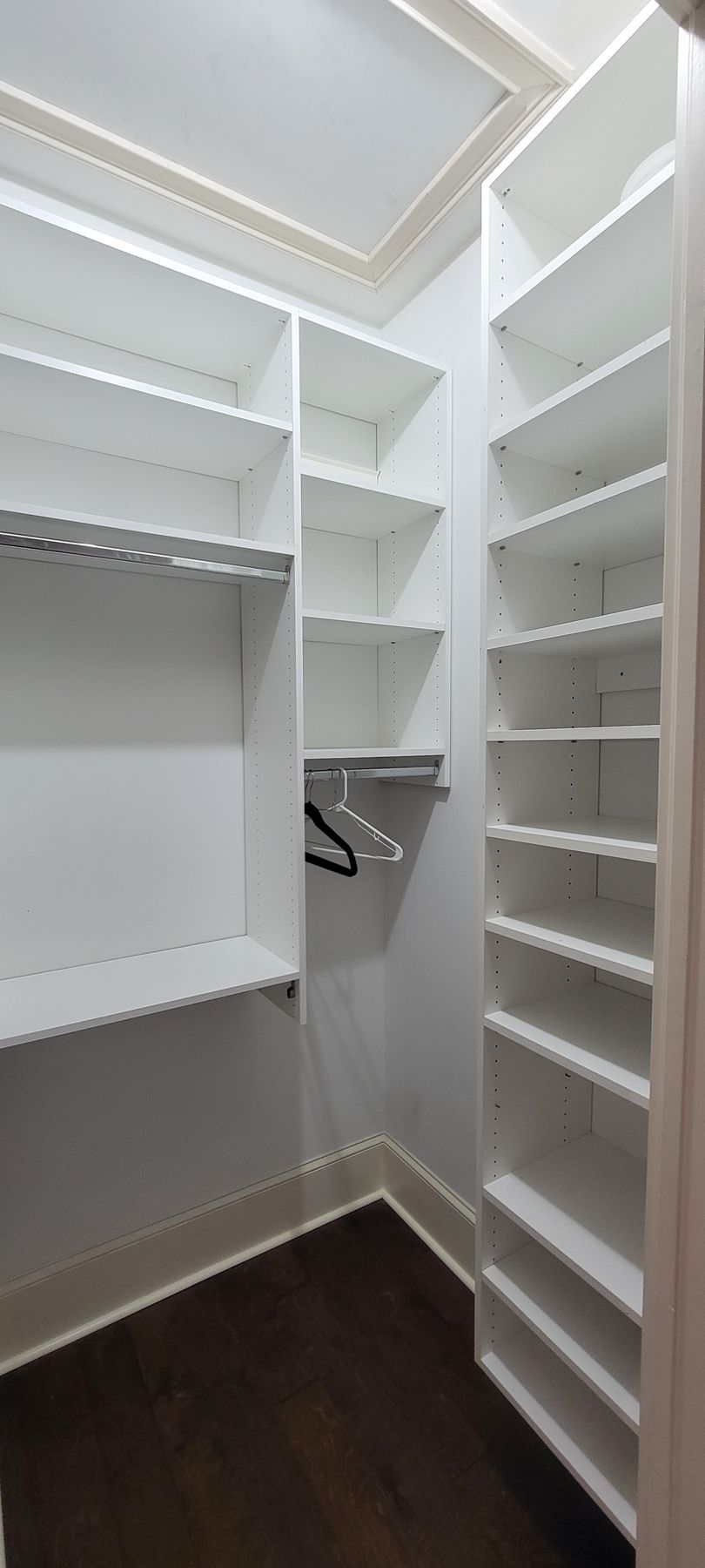 A walk in closet with lots of shelves and a hanger.
