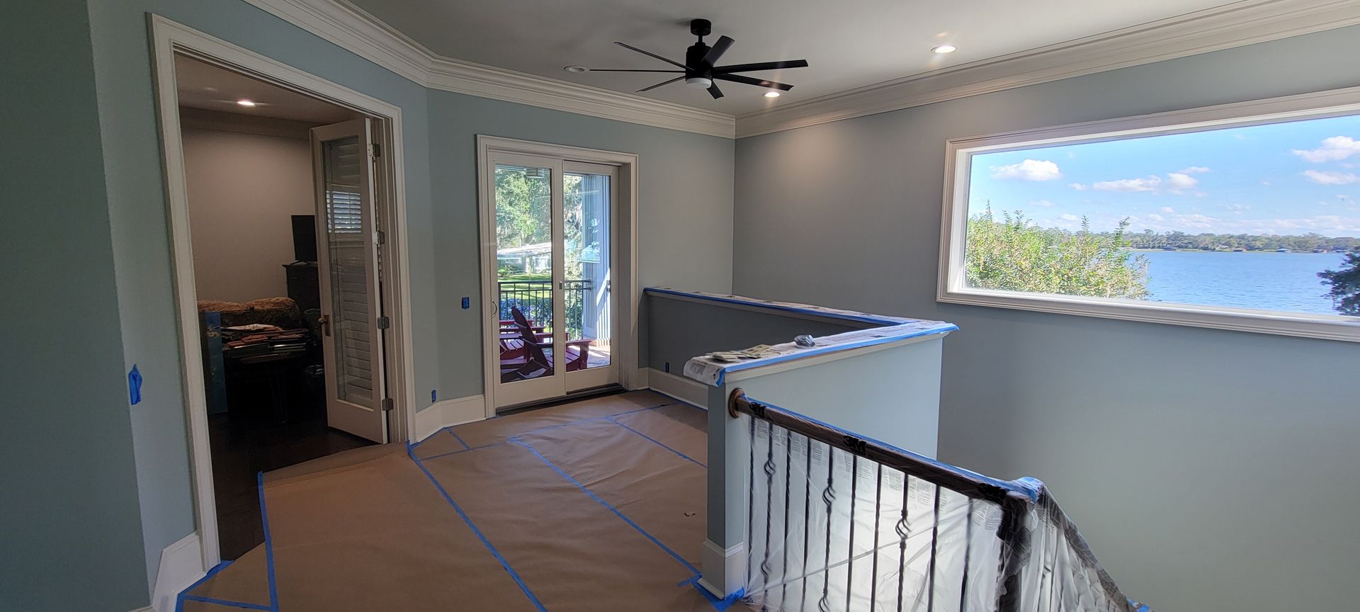 A room with a ceiling fan and a window with a view of a lake.