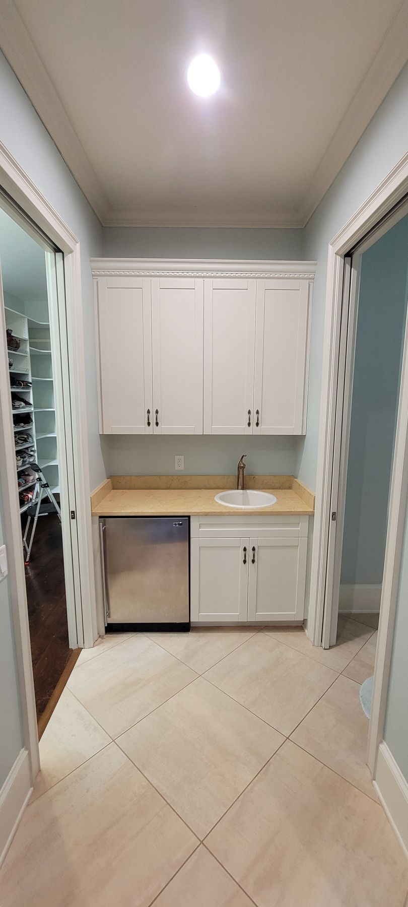 A kitchen with white cabinets , a sink , and a dishwasher.
