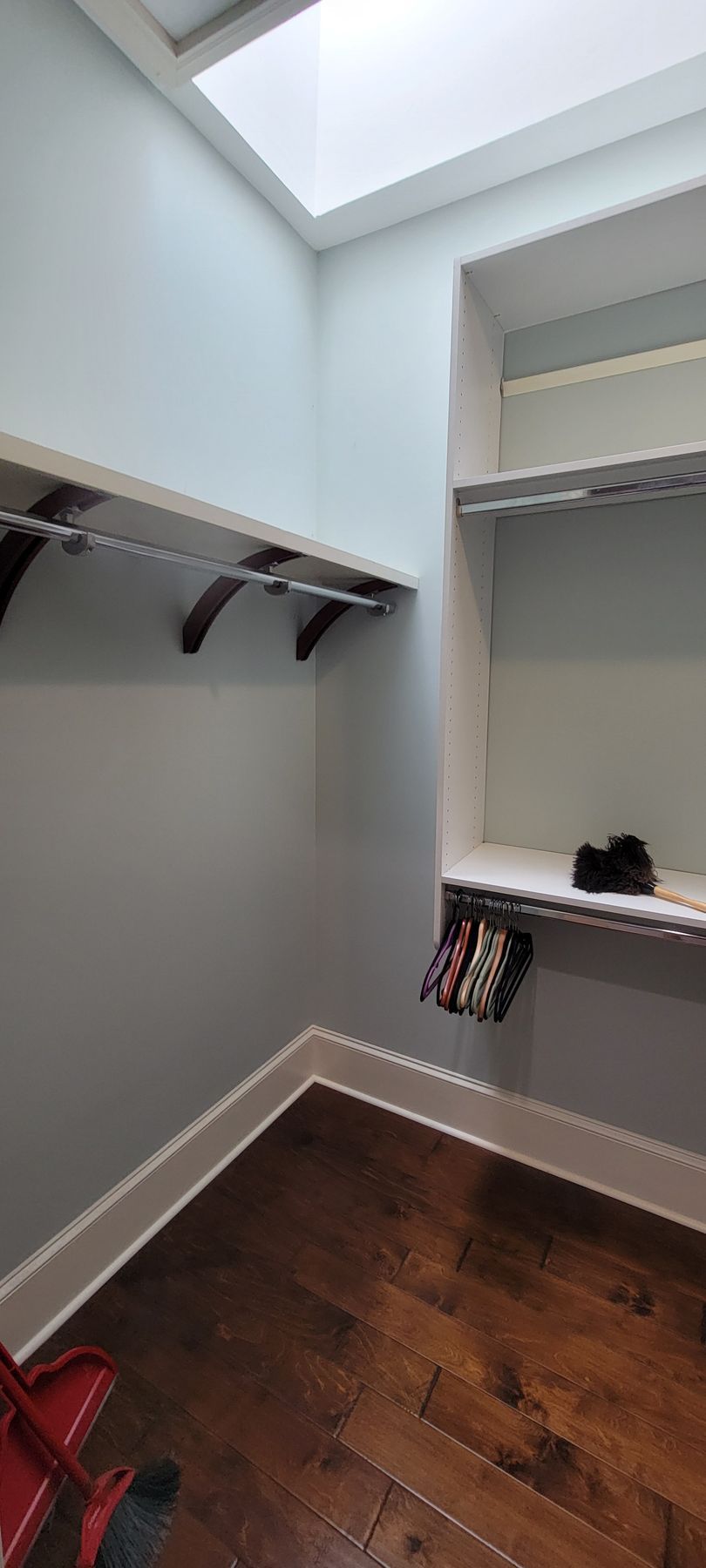 A walk in closet with hardwood floors and a skylight.