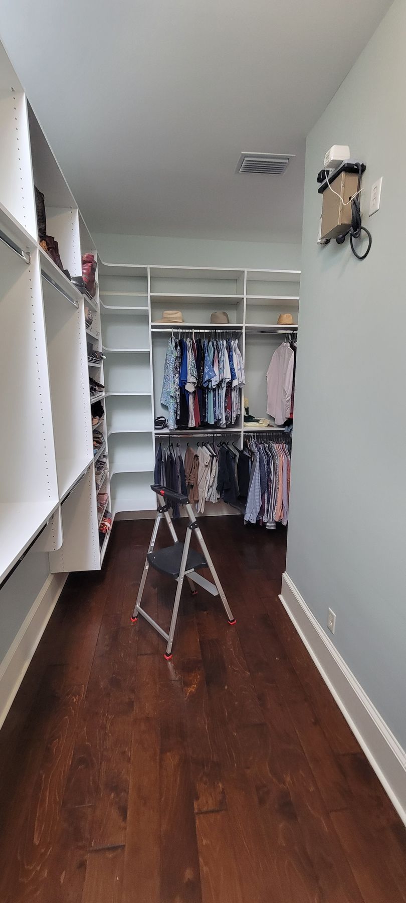 A walk in closet with a ladder in the middle of it.