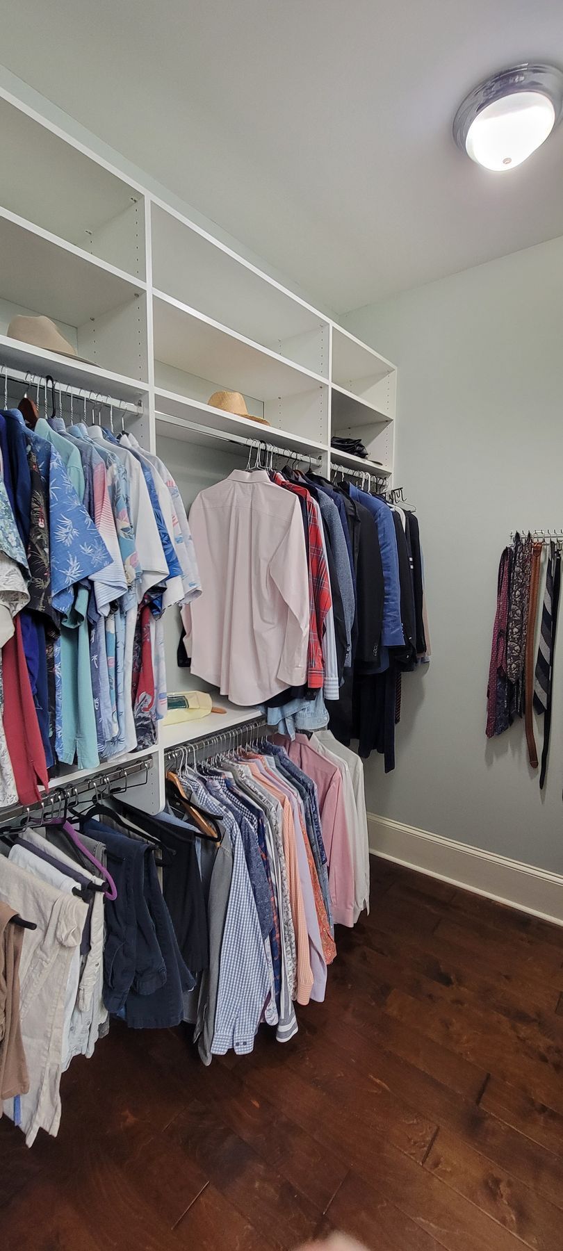 A walk in closet filled with lots of clothes hanging on racks.
