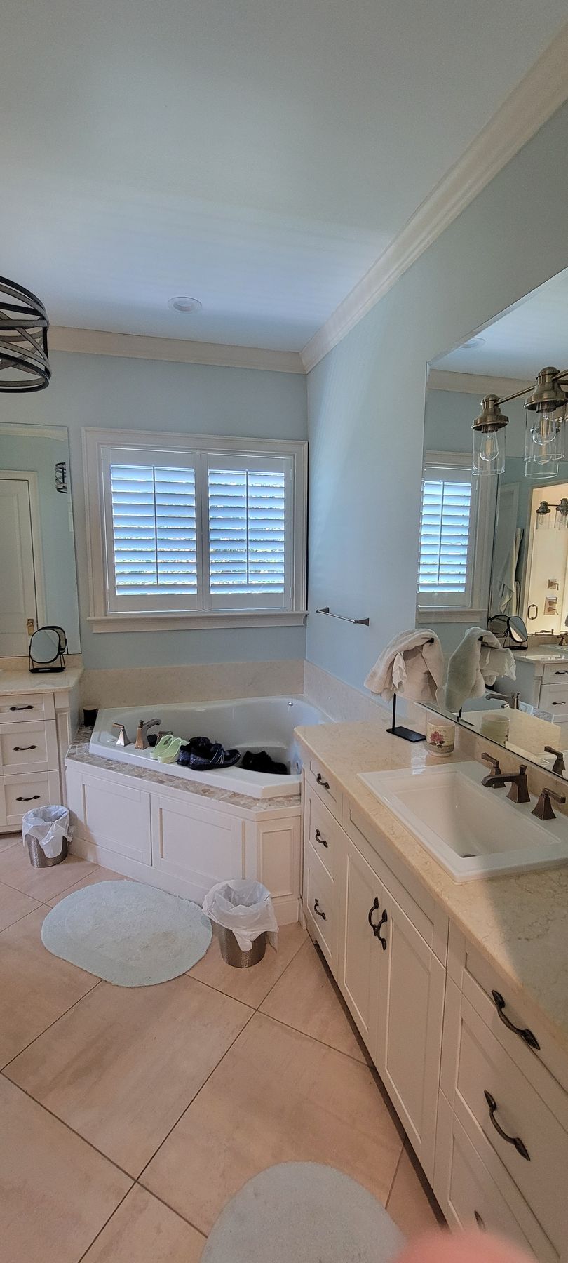 A bathroom with a tub , sink , mirror and window.