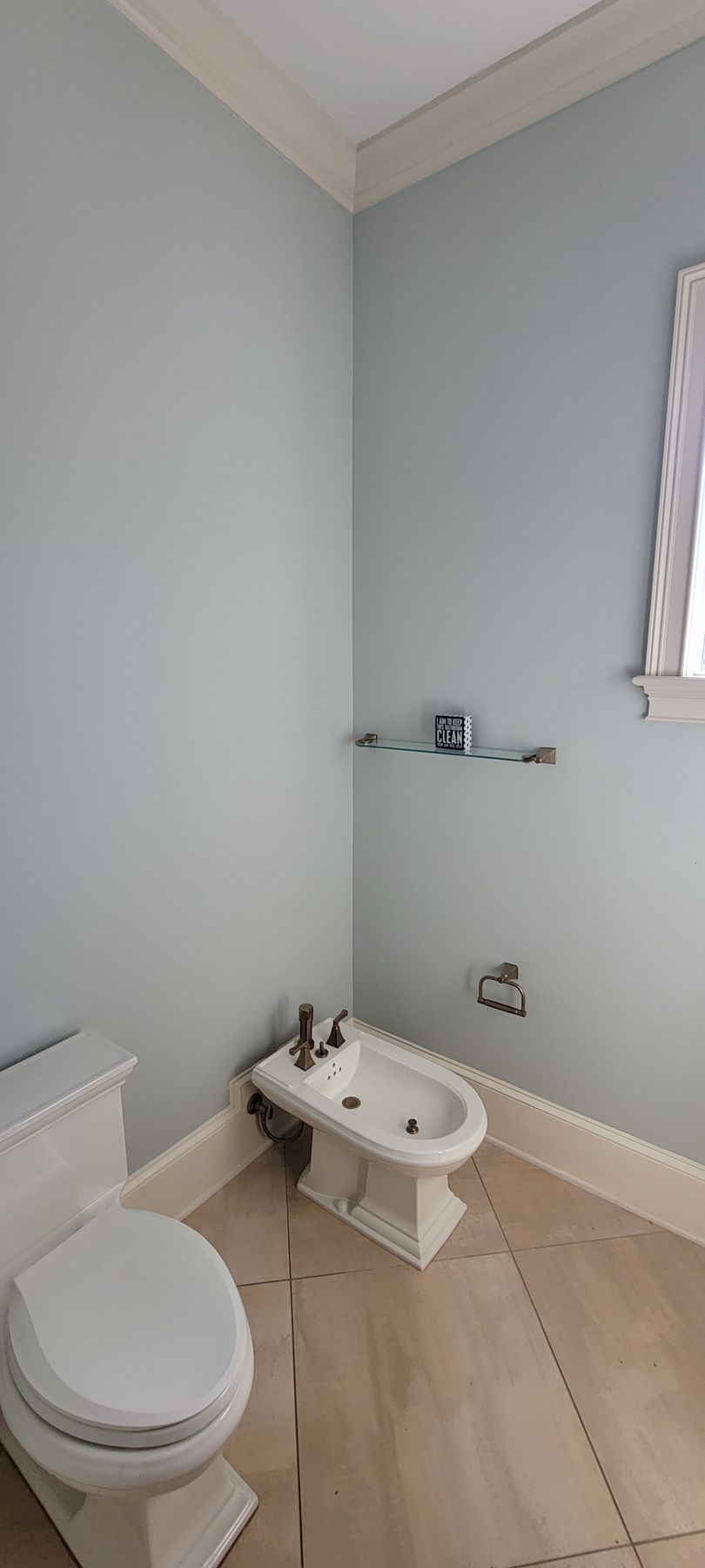 A bathroom with a toilet , bidet and window.