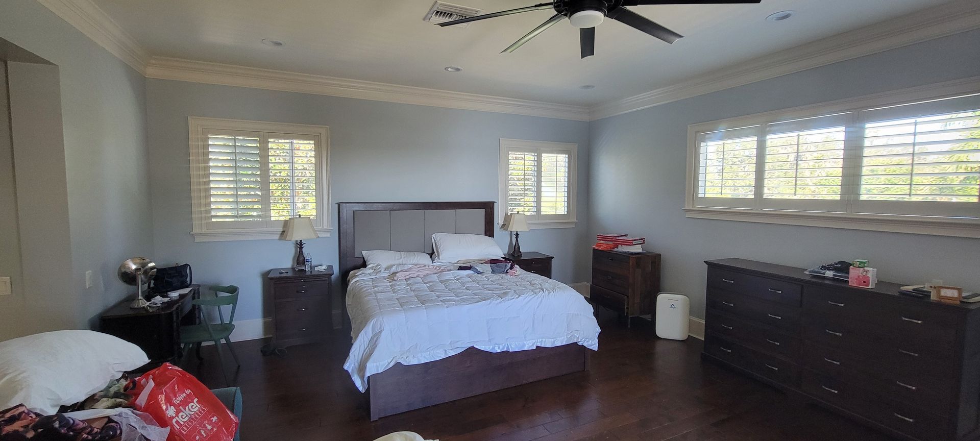 A bedroom with a bed , dresser , nightstand , and ceiling fan.