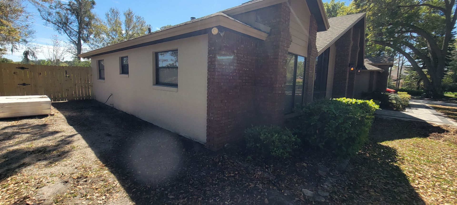 The side of a house with a fence and a lot of windows.