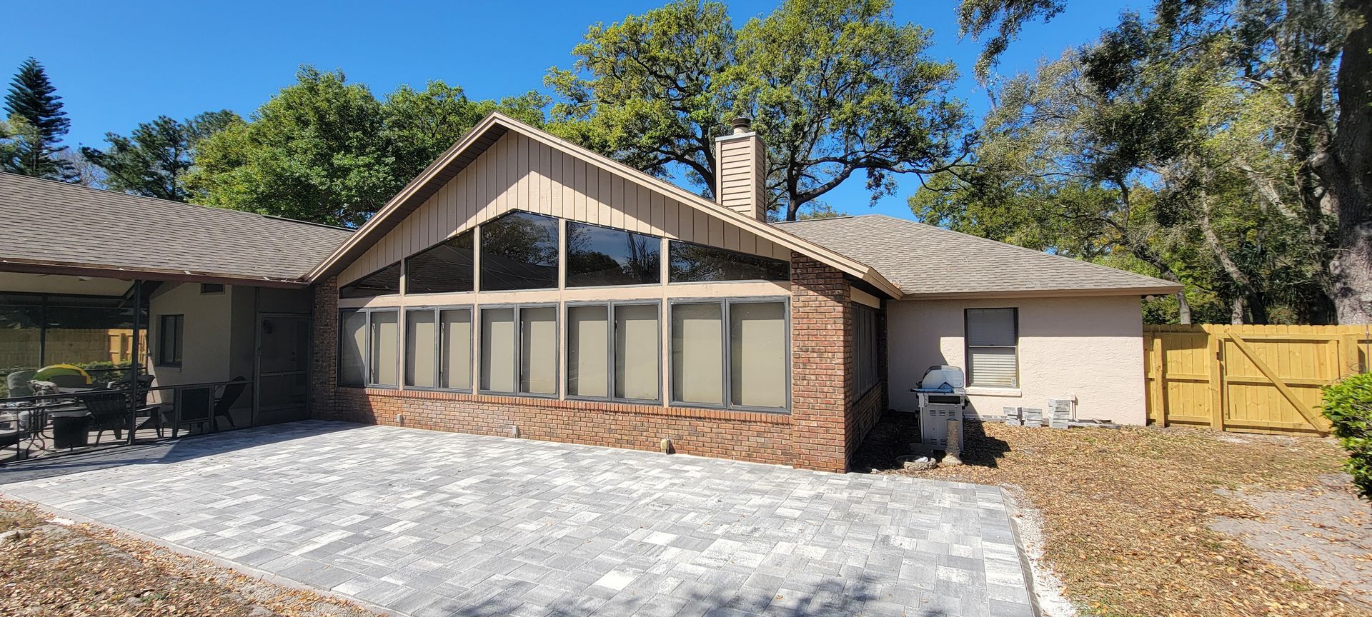 A house with a screened in porch and a patio in front of it.
