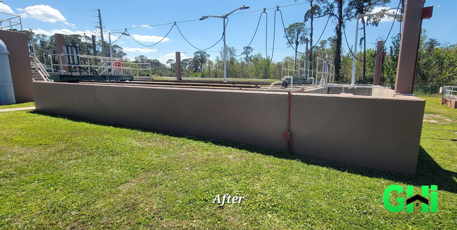A large concrete wall is sitting in the middle of a lush green field.