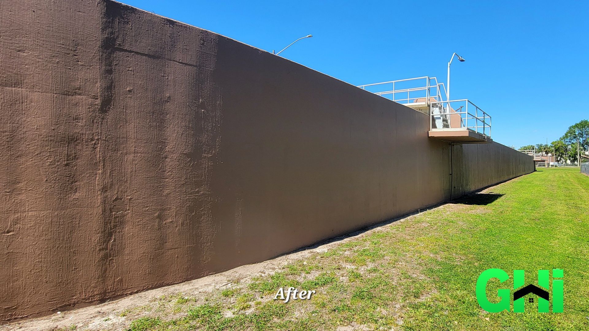 A large brown wall is sitting in the middle of a grassy field.