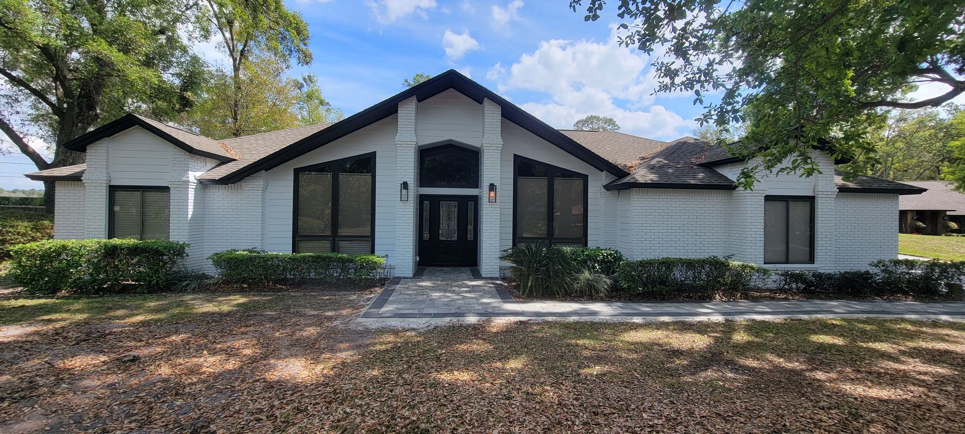 A white house with black windows and a black roof is for sale.