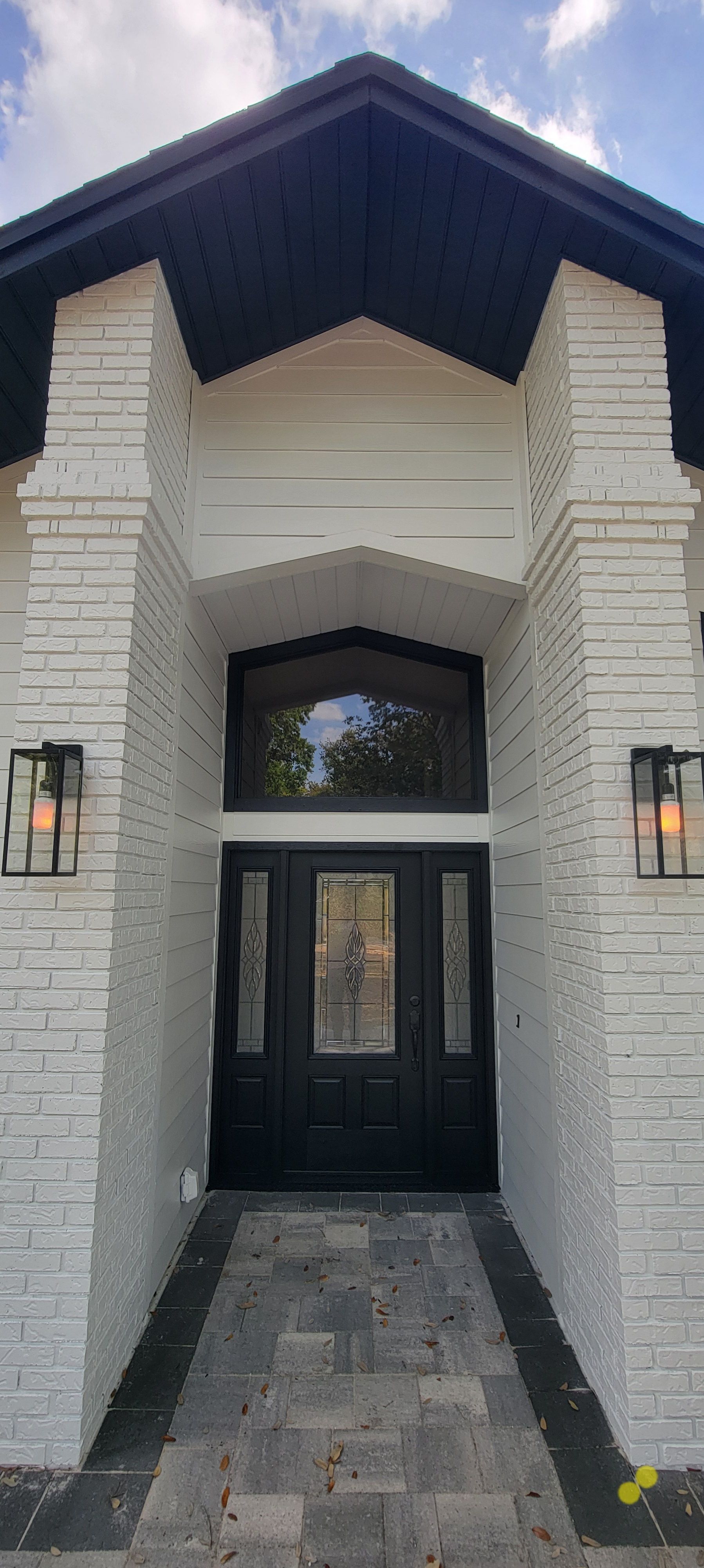 A white brick house with a black door and a black roof.