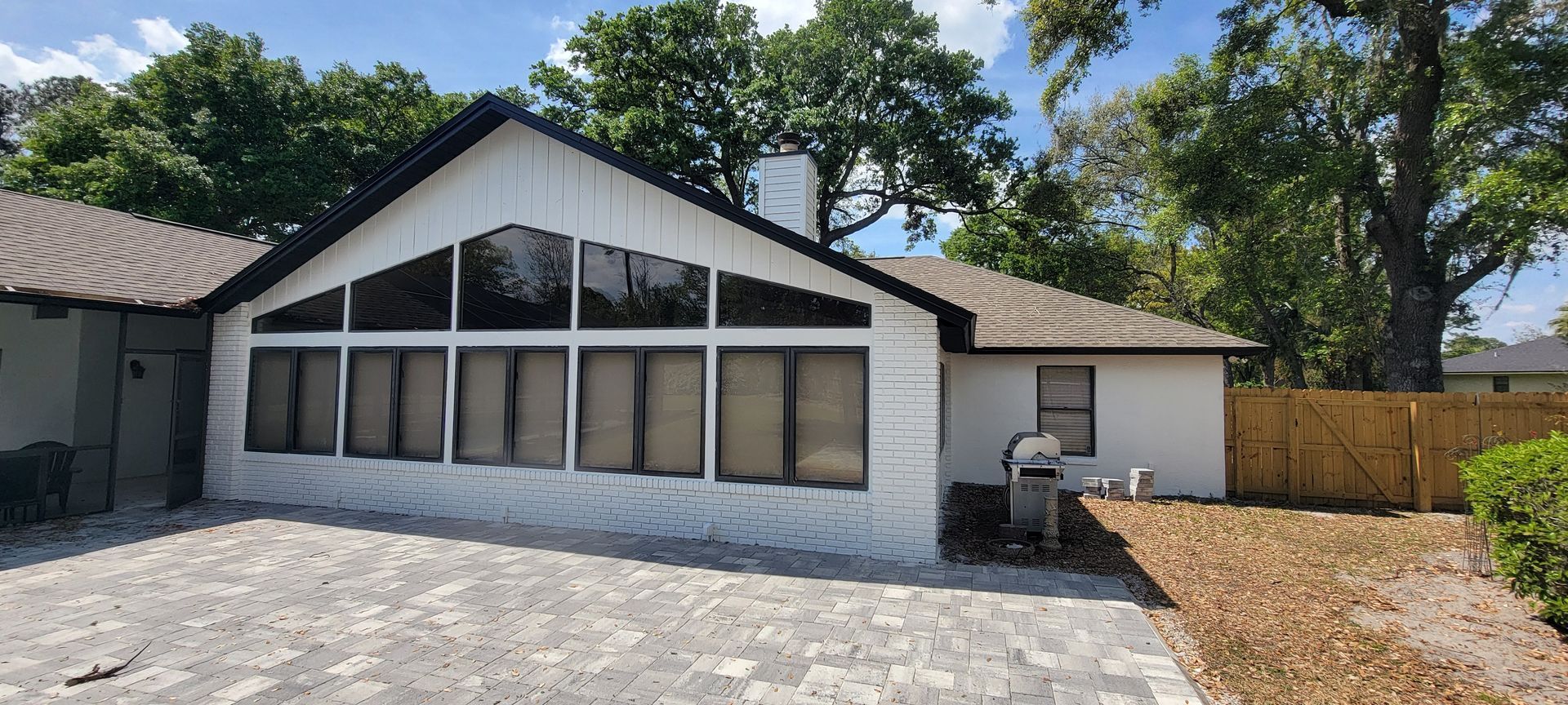 A white house with a lot of windows and a grill in front of it.