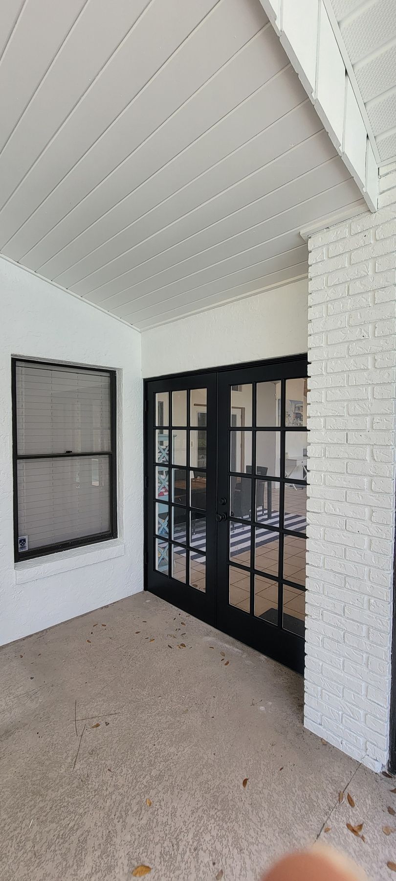 A person is standing in a room with white walls and black french doors.