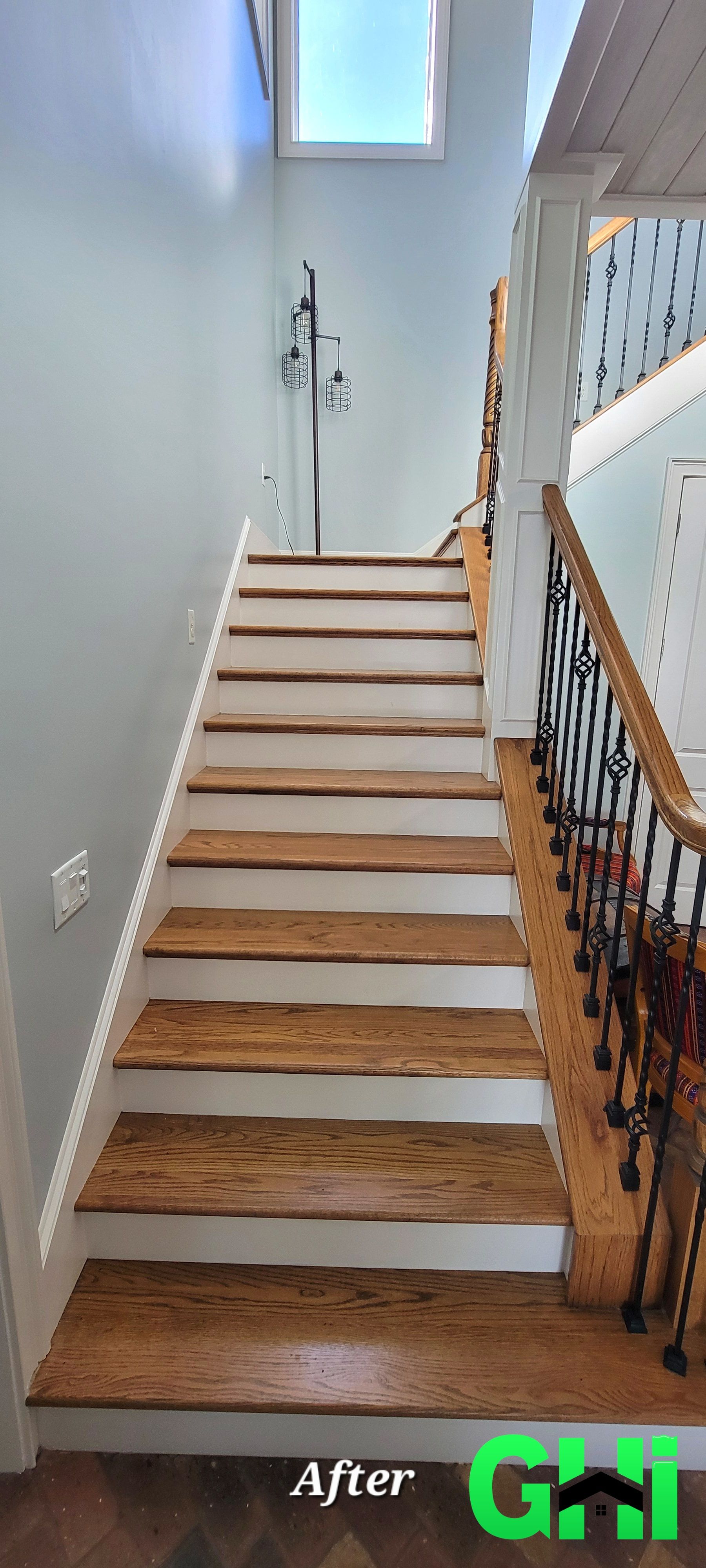 A picture of a wooden staircase with white steps and a wrought iron railing.