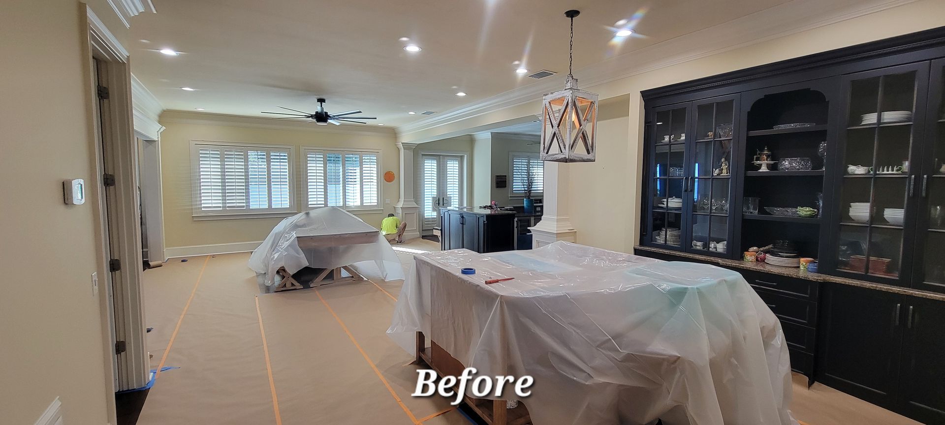 A living room with a table and a pool table covered in plastic.