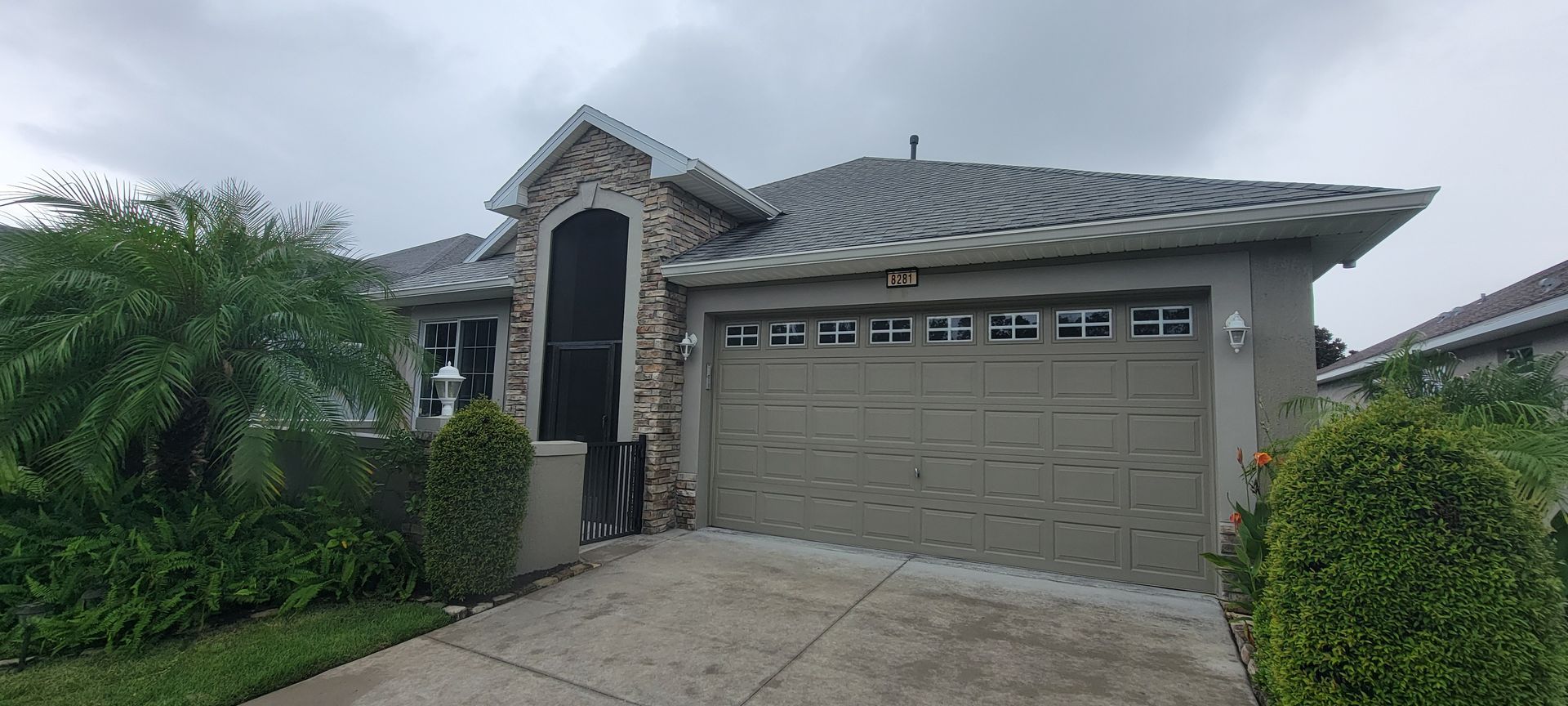 A house with a large garage door and a screened in porch.