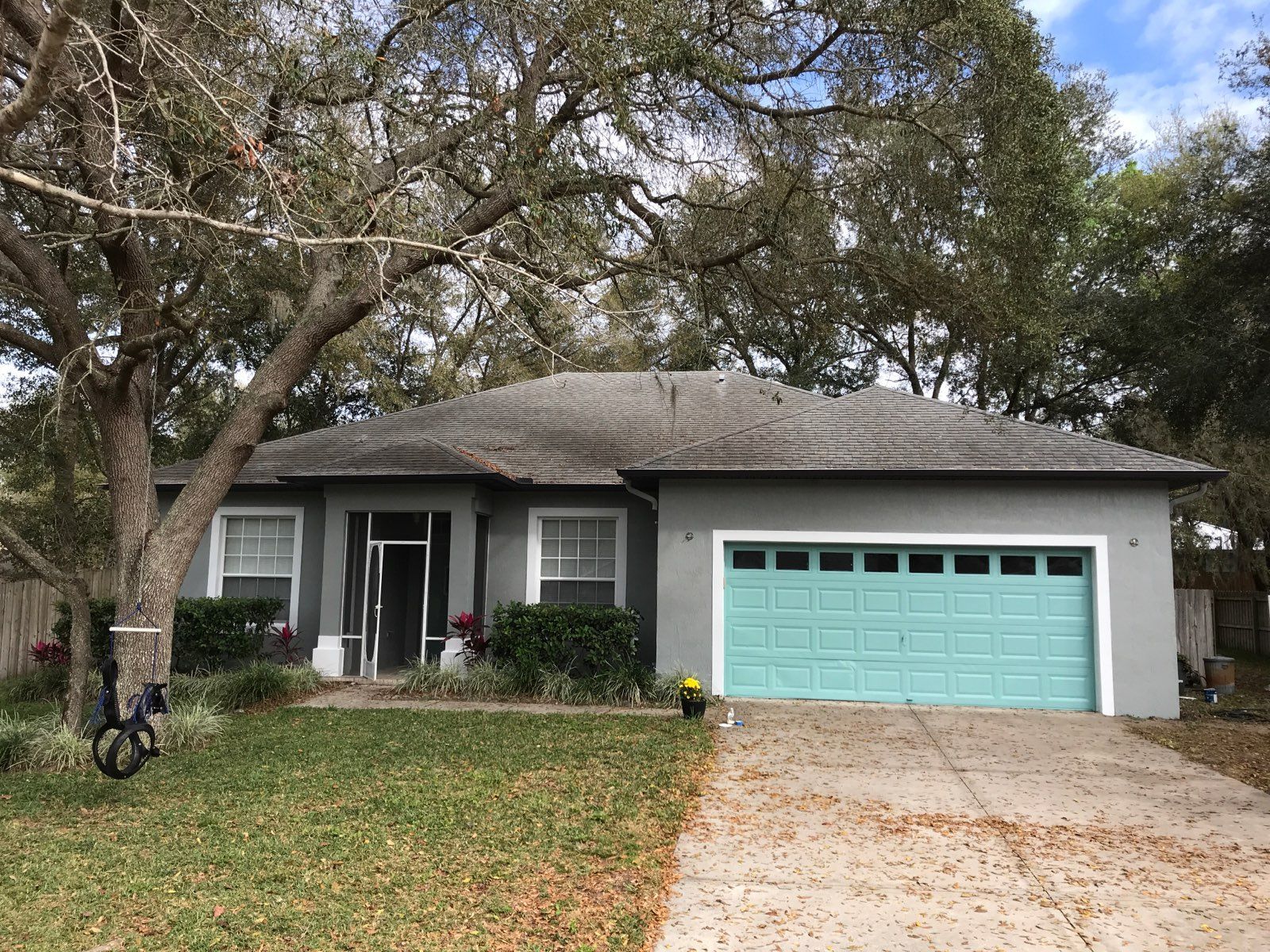 A house with a blue garage door and a tree in front of it.
