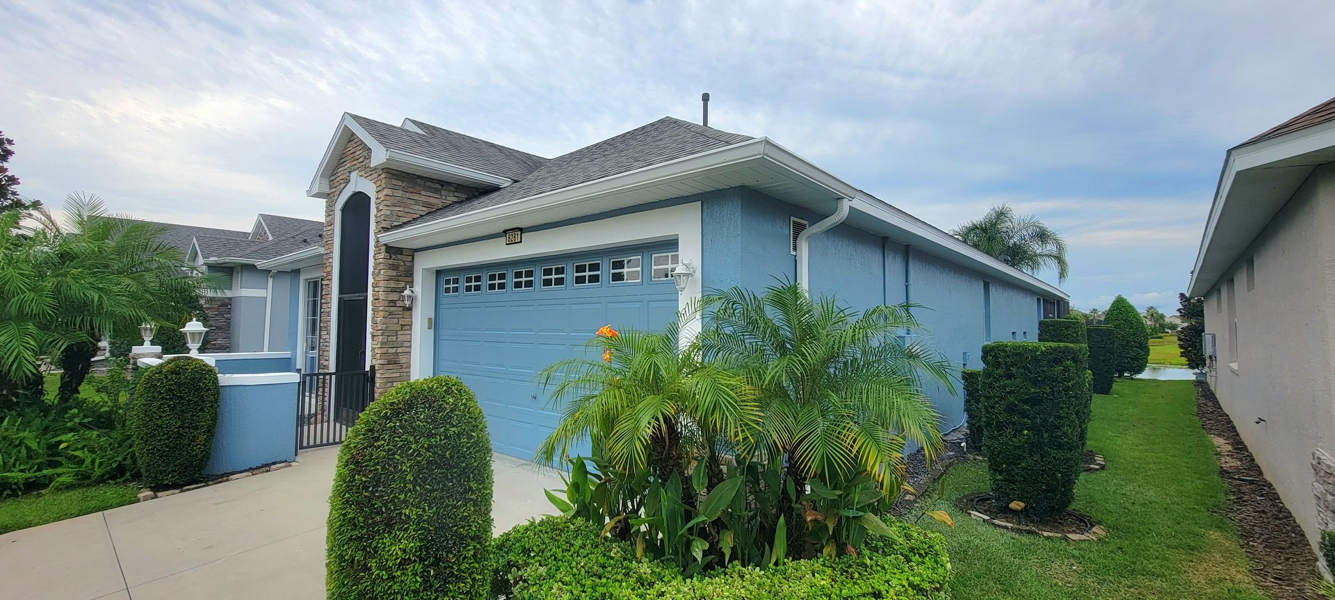 A blue house with a white garage door and a gray roof.