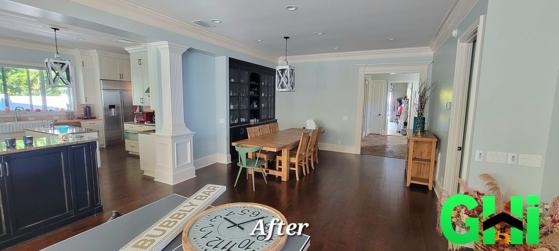 A living room with a dining table and chairs and a clock on the table.