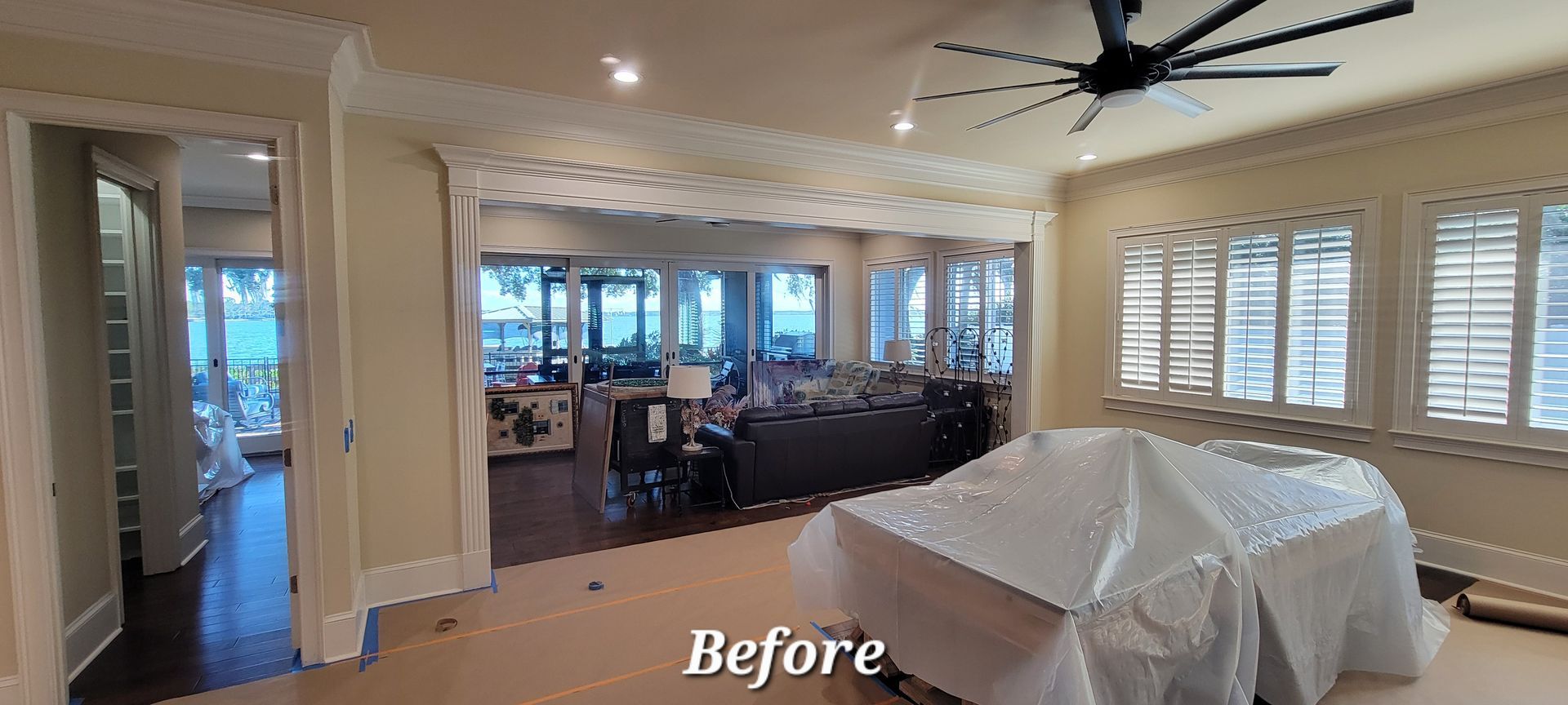 A before picture of a living room with a pool table and a ceiling fan.