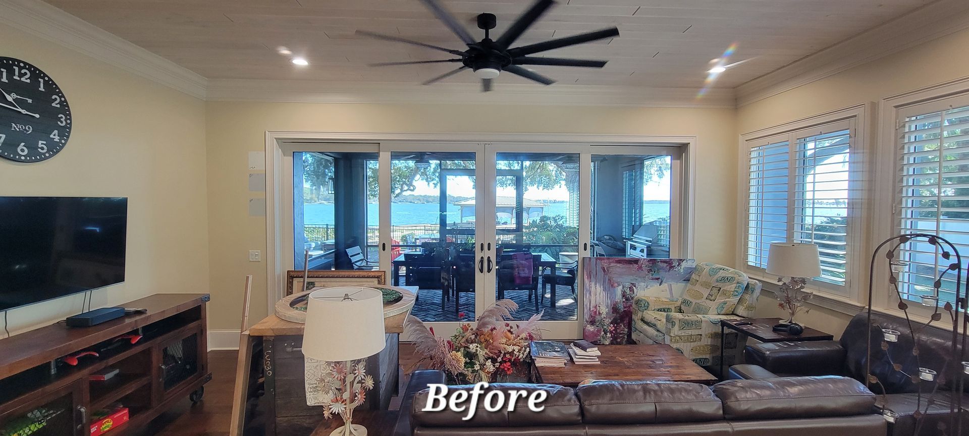 A living room with a lot of windows and a ceiling fan.