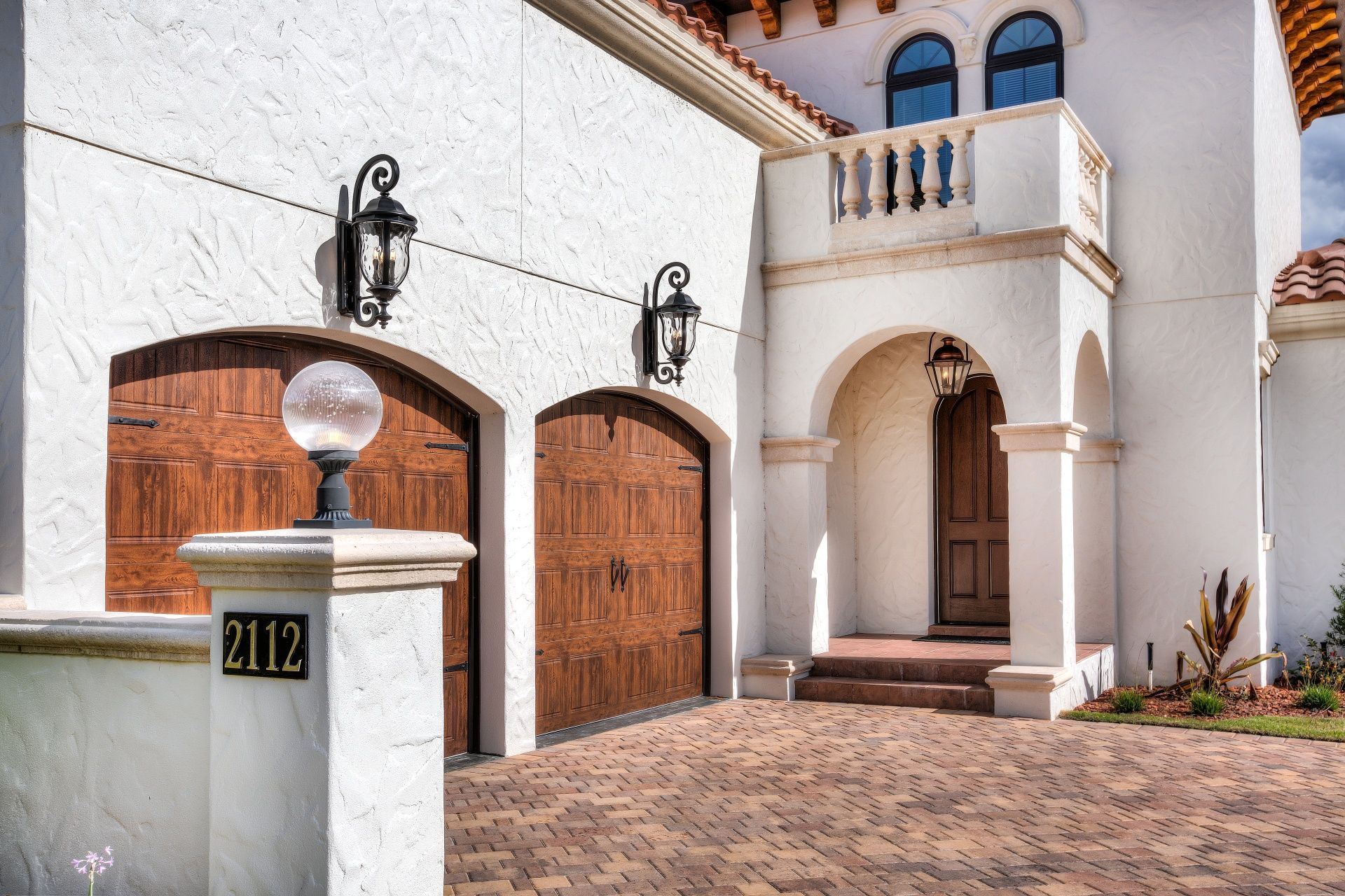 A white house with a brick driveway and a sign that says 212