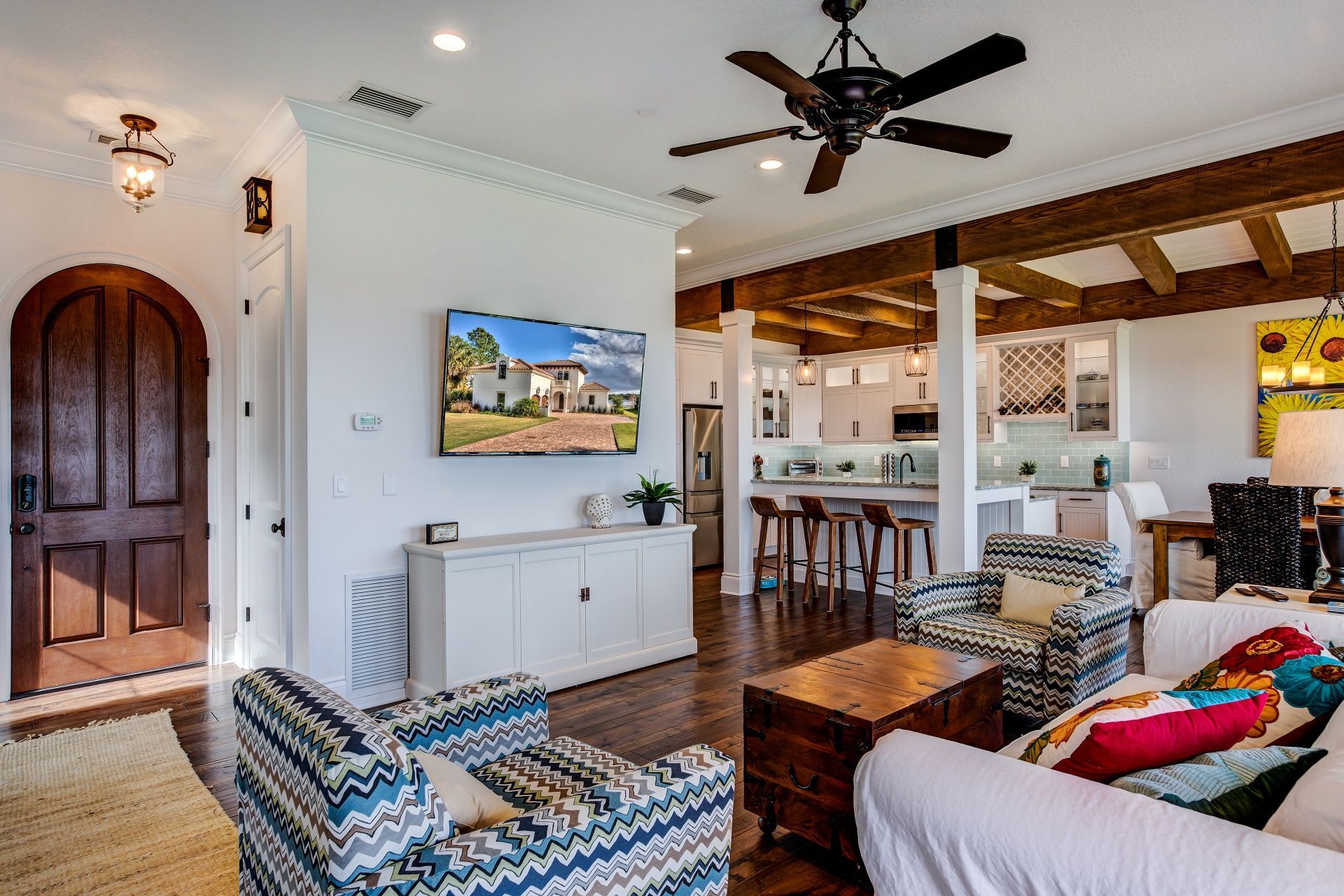 A living room with a couch , chairs , a television and a ceiling fan.