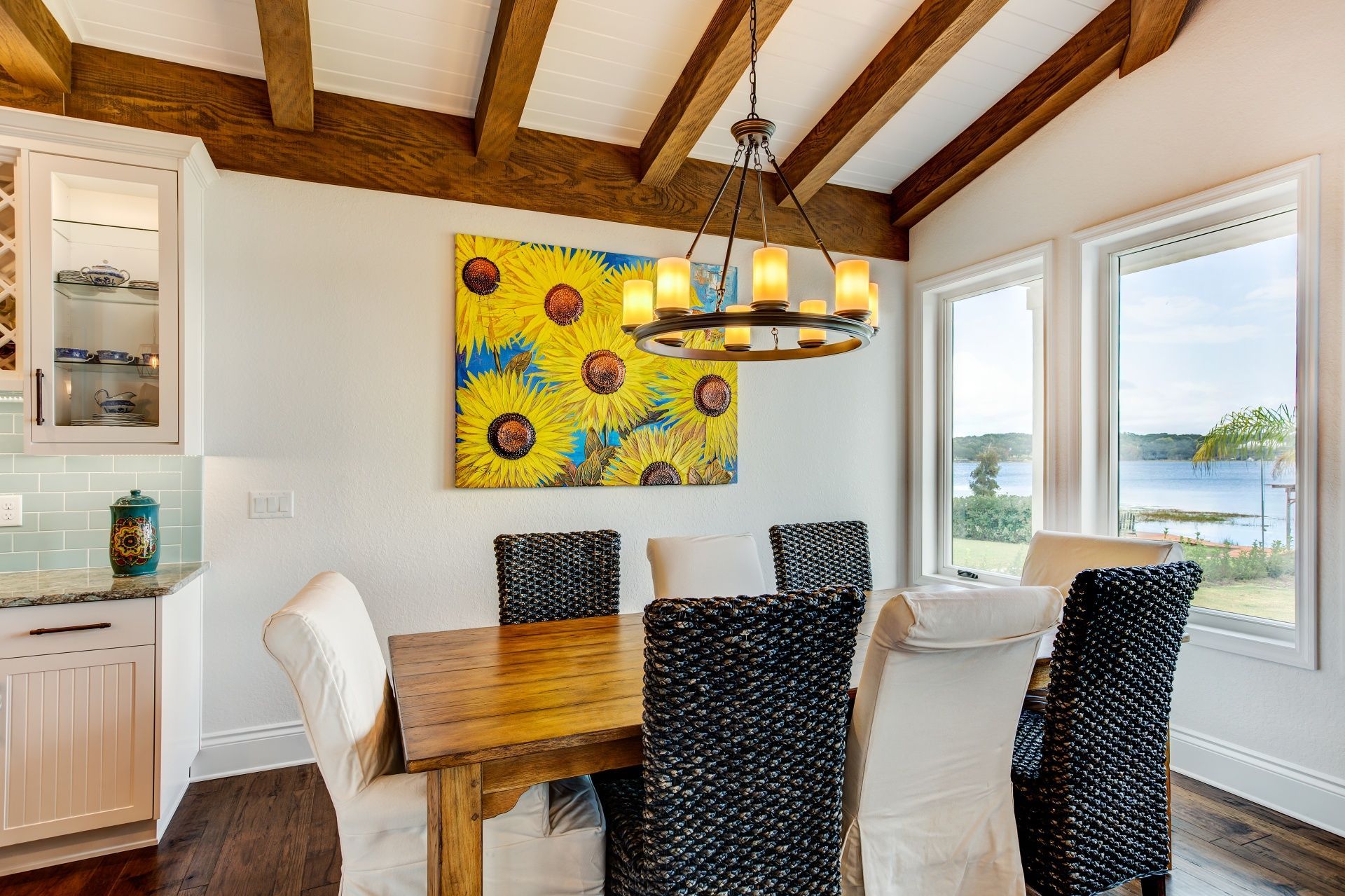 A dining room with a table and chairs and a painting on the wall.