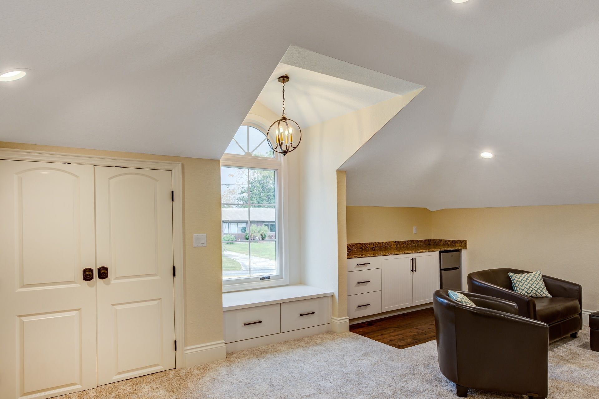 A living room with two chairs , a couch , and a window.