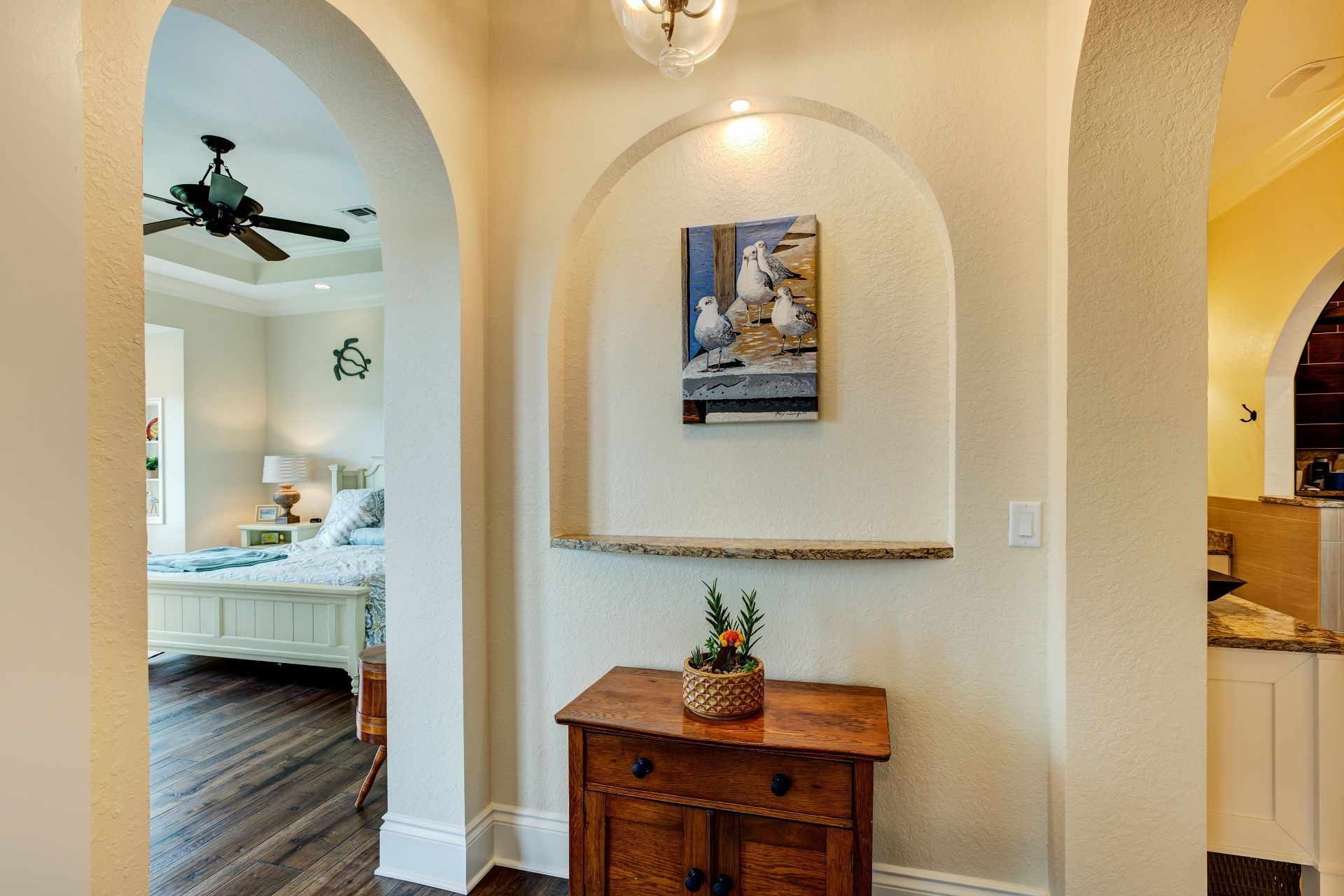 There is a painting on the wall above the dresser in the hallway.