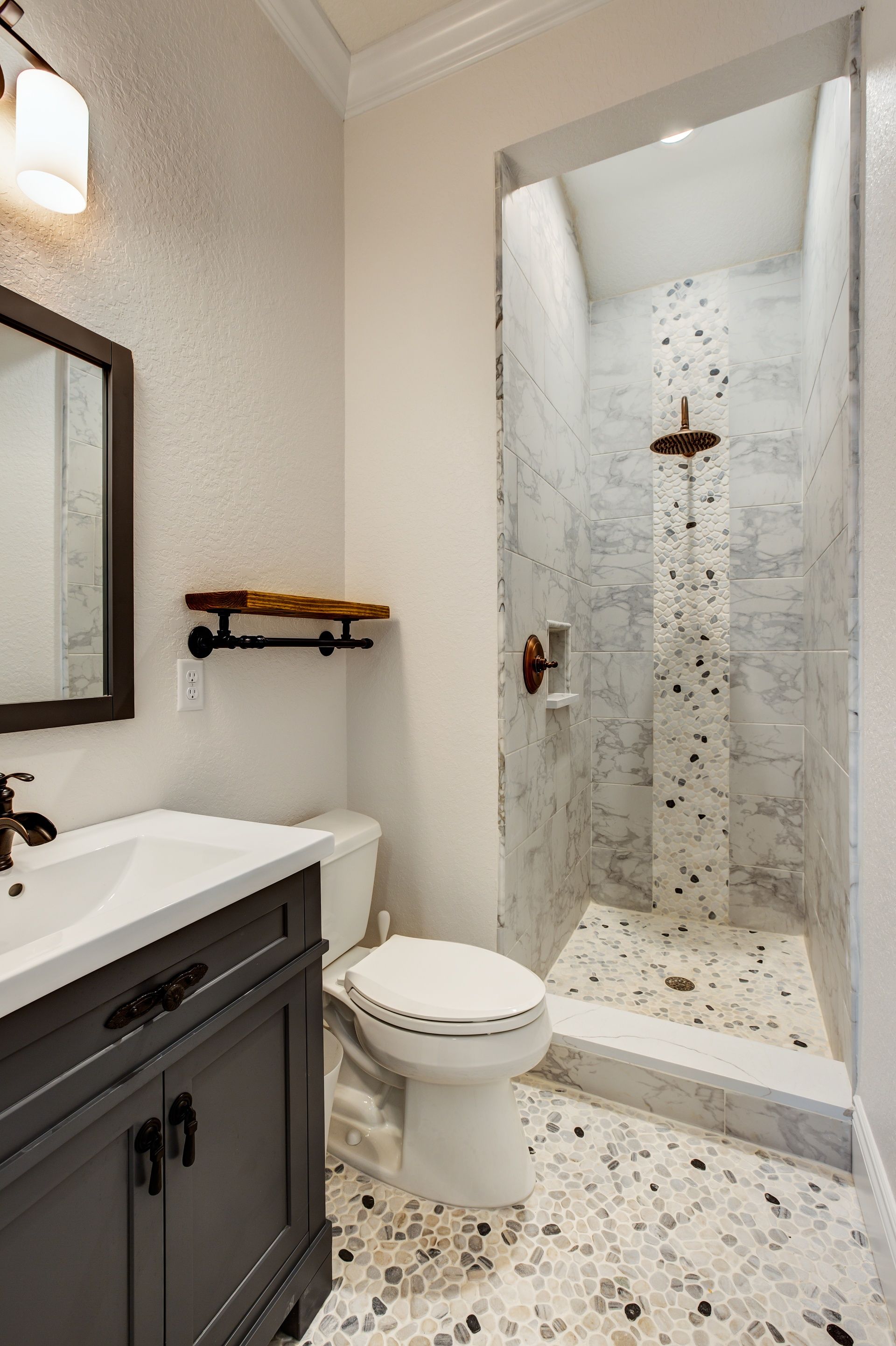 A bathroom with a toilet , sink , mirror and walk in shower.
