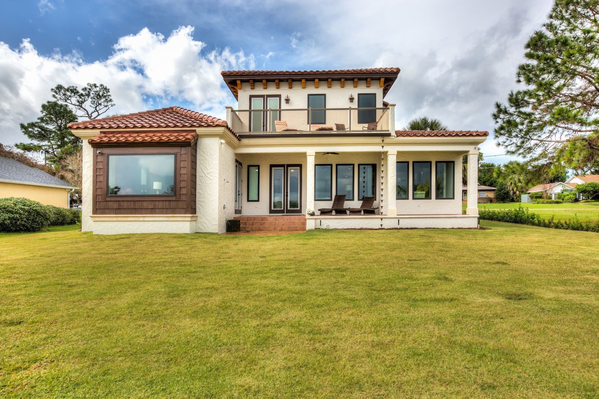 A large house with a lot of windows is sitting on top of a lush green field