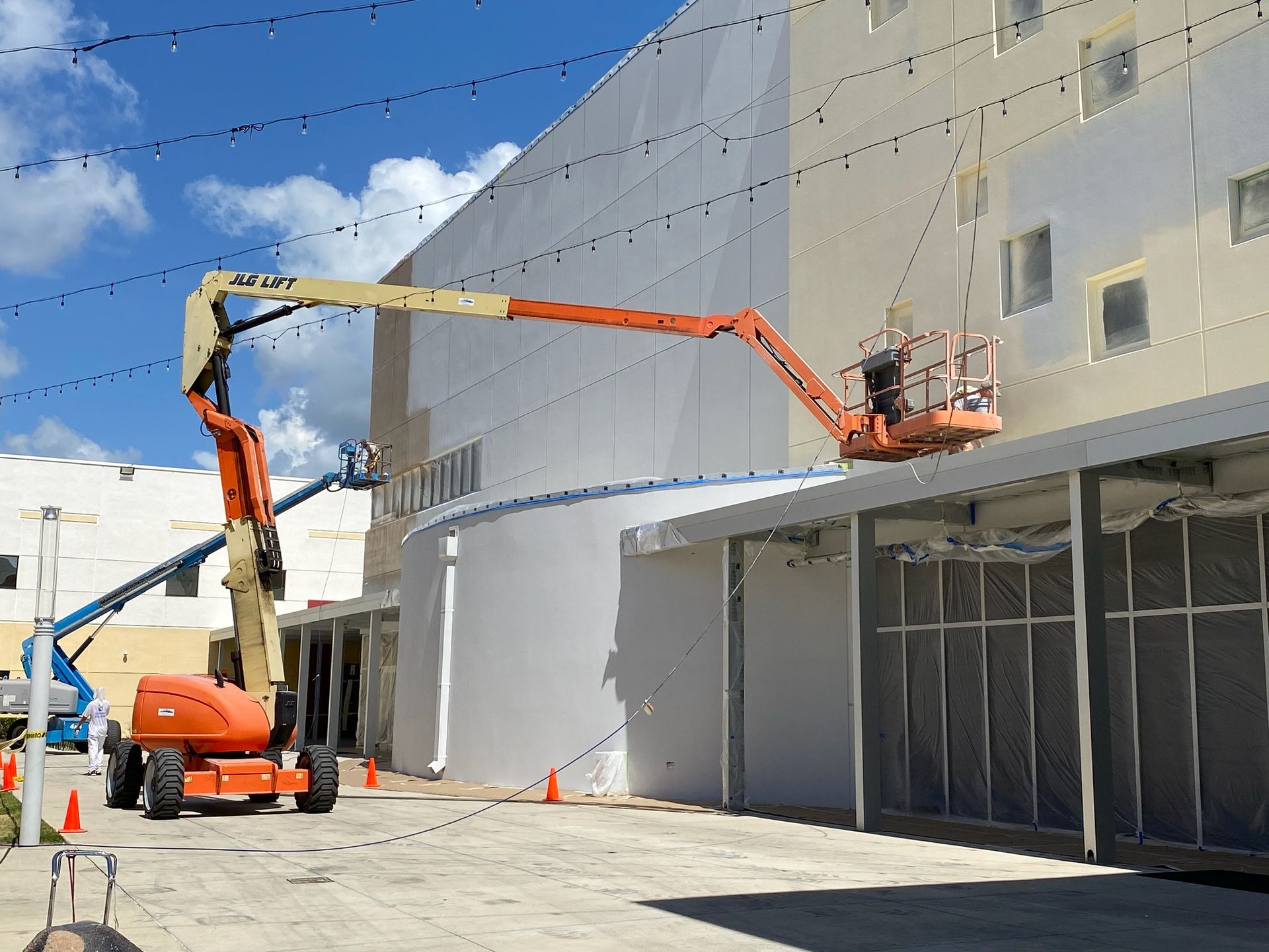 A jlg lift is being used to paint a building