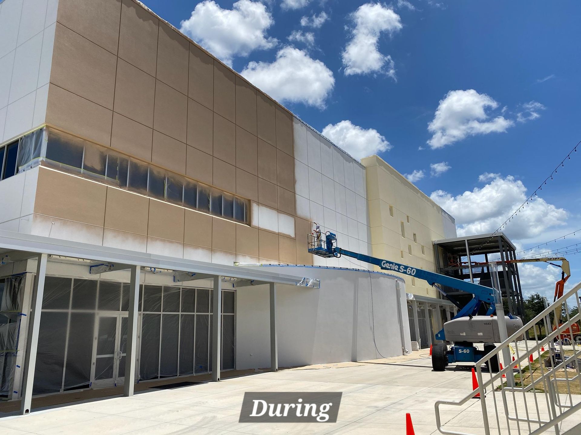 A large building is being painted white during construction.