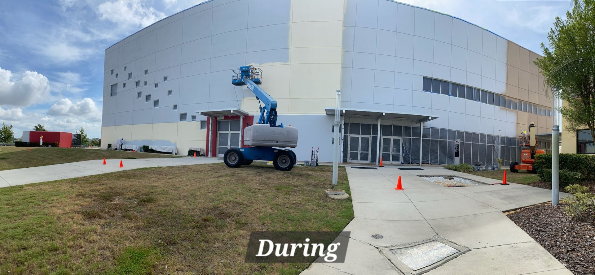 A large building is being painted with a crane.