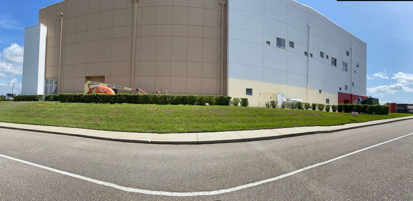 A large white building is sitting on the corner of a road.