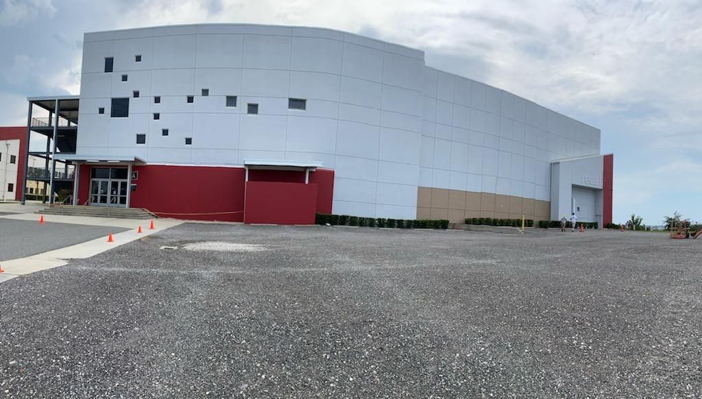A large white and red building with a parking lot in front of it.