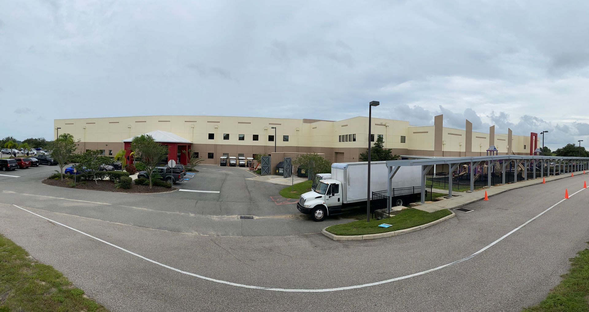 A white truck is parked in front of a large building.