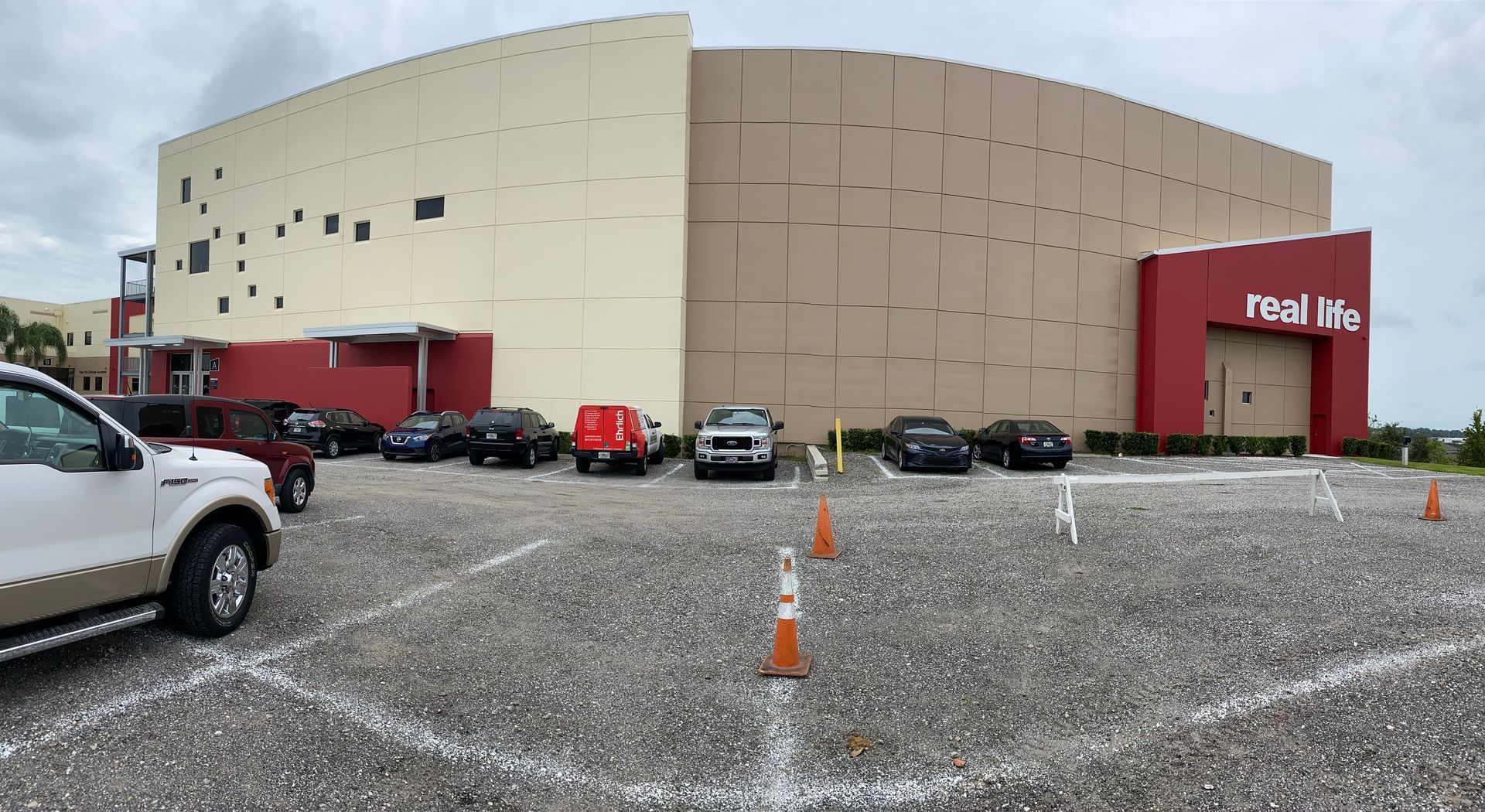 A parking lot with cars parked in front of a large building.