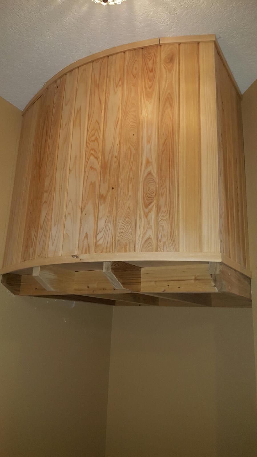 A wooden cabinet is hanging from the ceiling in a kitchen.