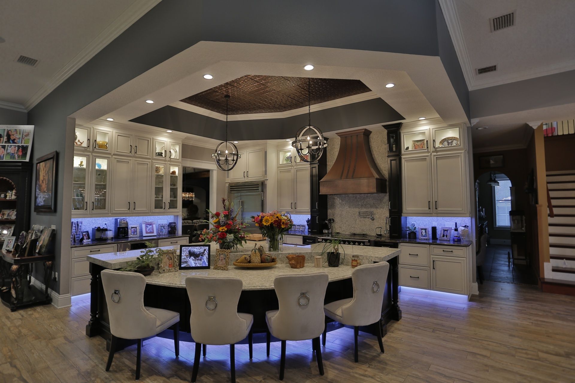 A large kitchen with a large island in the middle and chairs around it.
