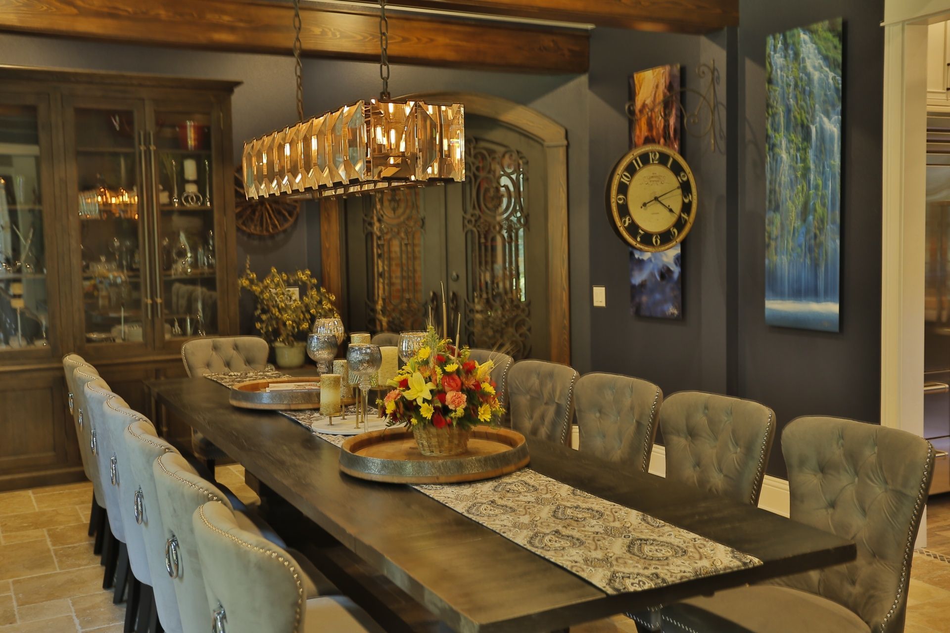 A dining room with a long table and chairs and a clock on the wall.