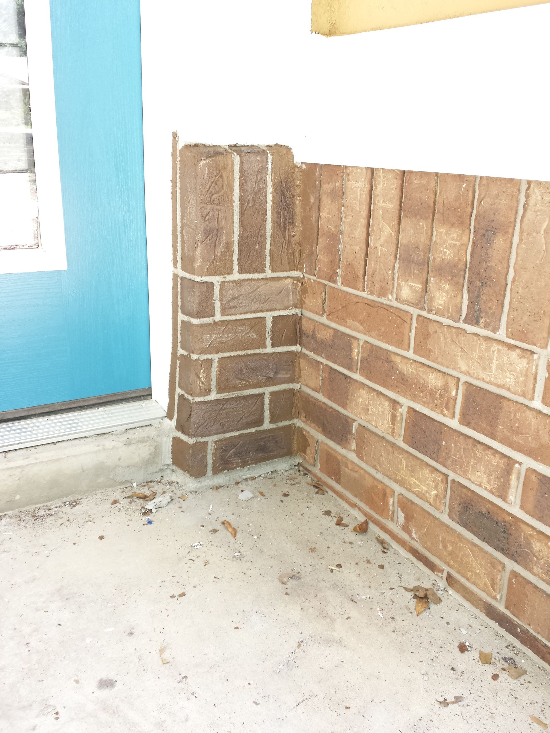 A brick wall with a blue door in the background