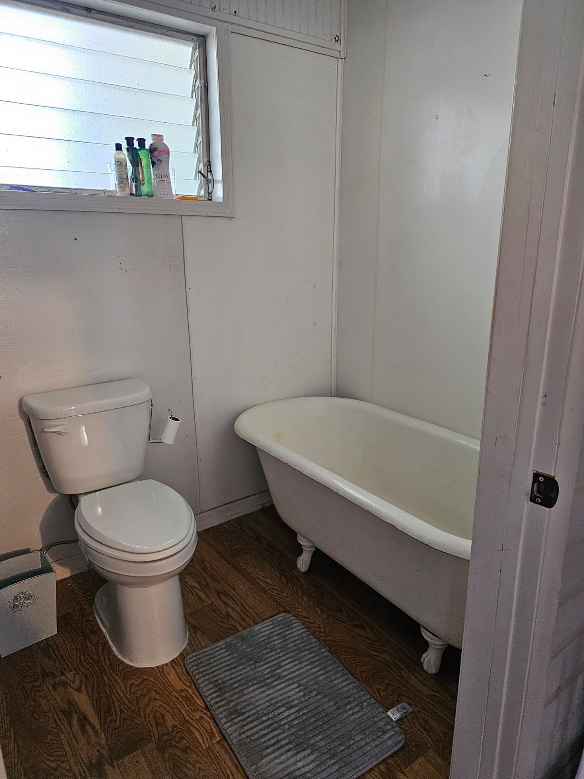A bathroom with a toilet , tub and window.