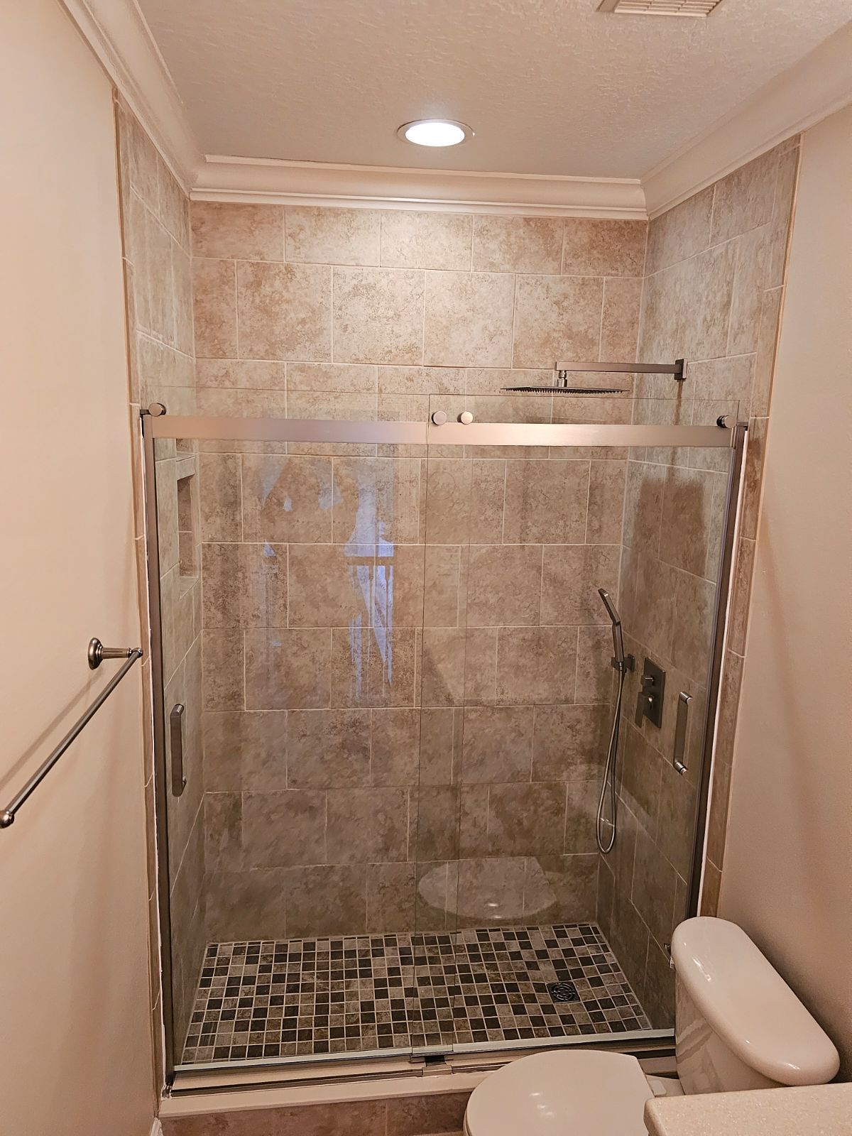 A bathroom with a sliding glass shower door and a toilet.