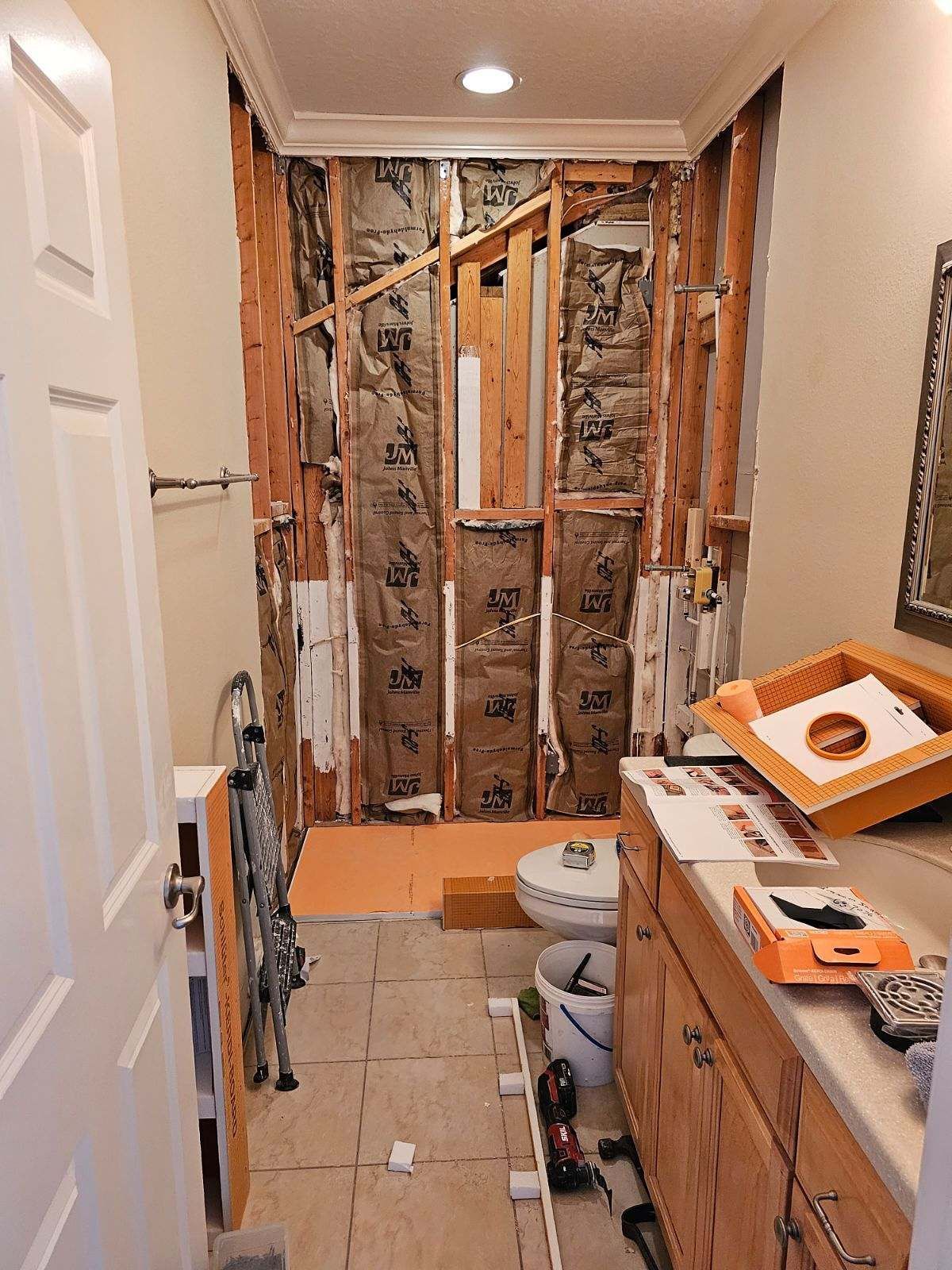 A bathroom under construction with a toilet , sink , and mirror.