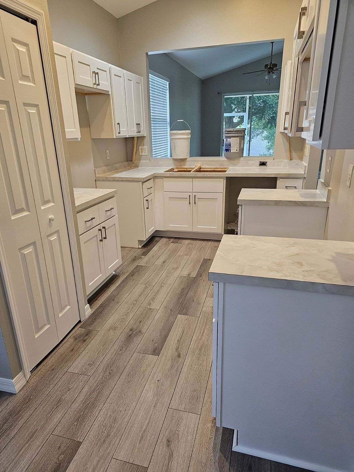 A kitchen with white cabinets and a wooden floor.