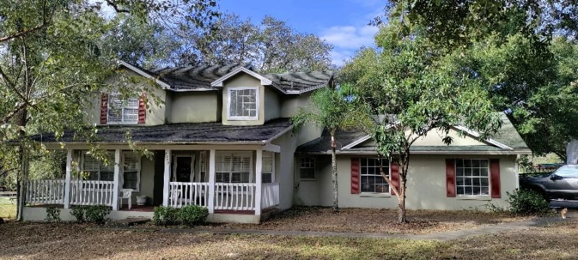 A large house with a porch and a car parked in front of it.