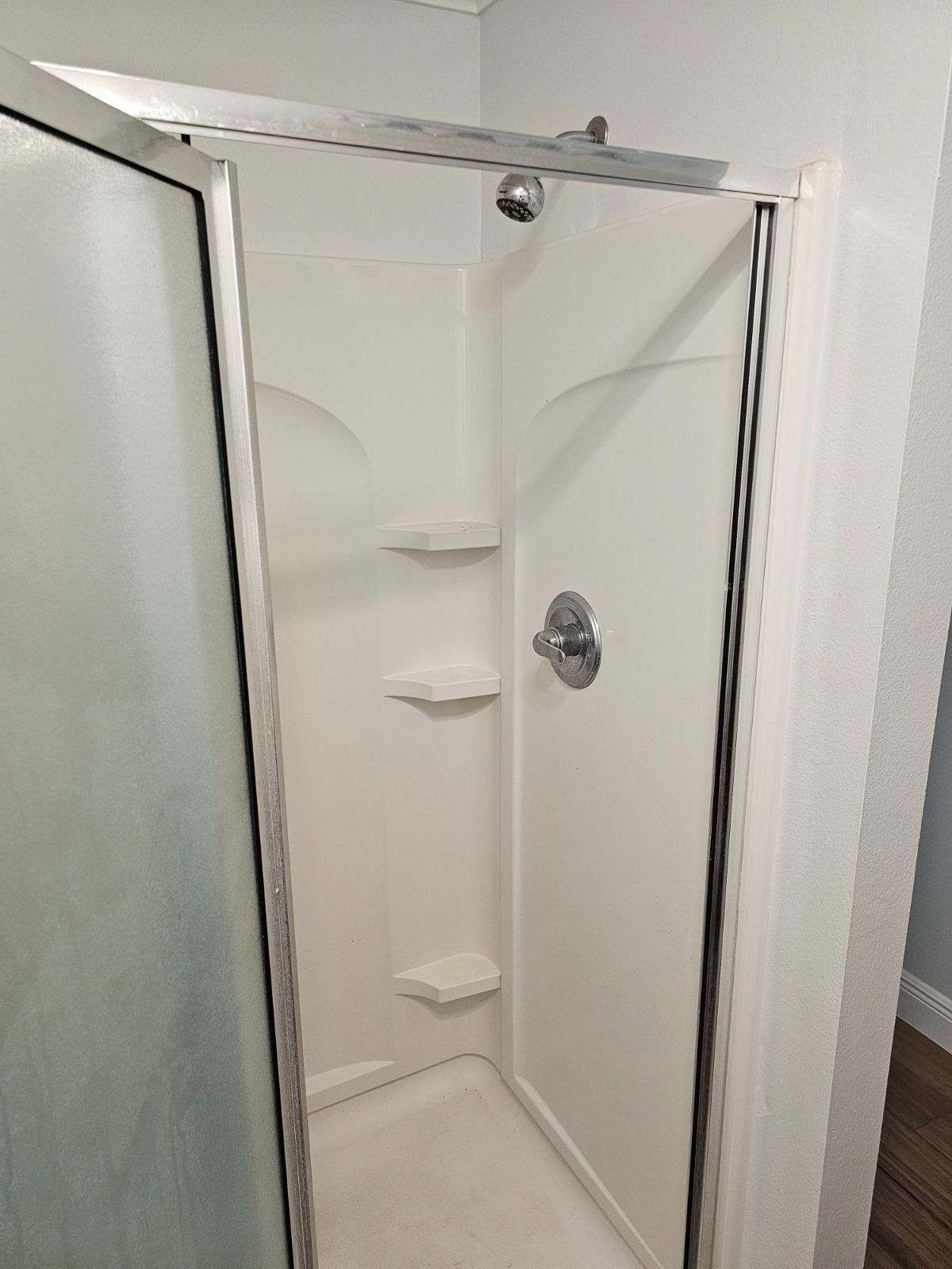 A shower stall with a glass door and a shower head.